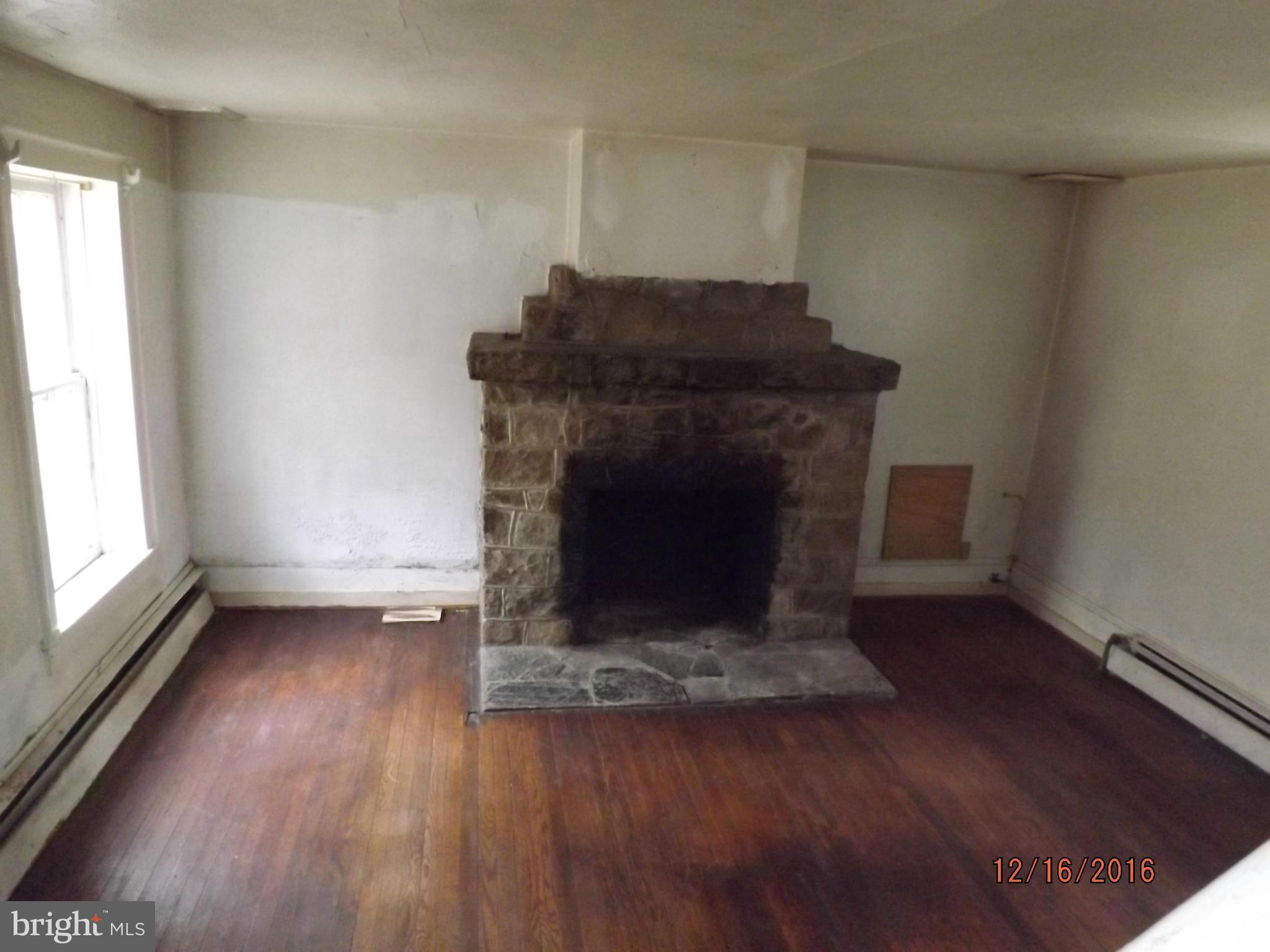 10 Big Spring Street Luray, VA 22835 - Photo 5 of 14 an empty room with wooden floor a fireplace and windows