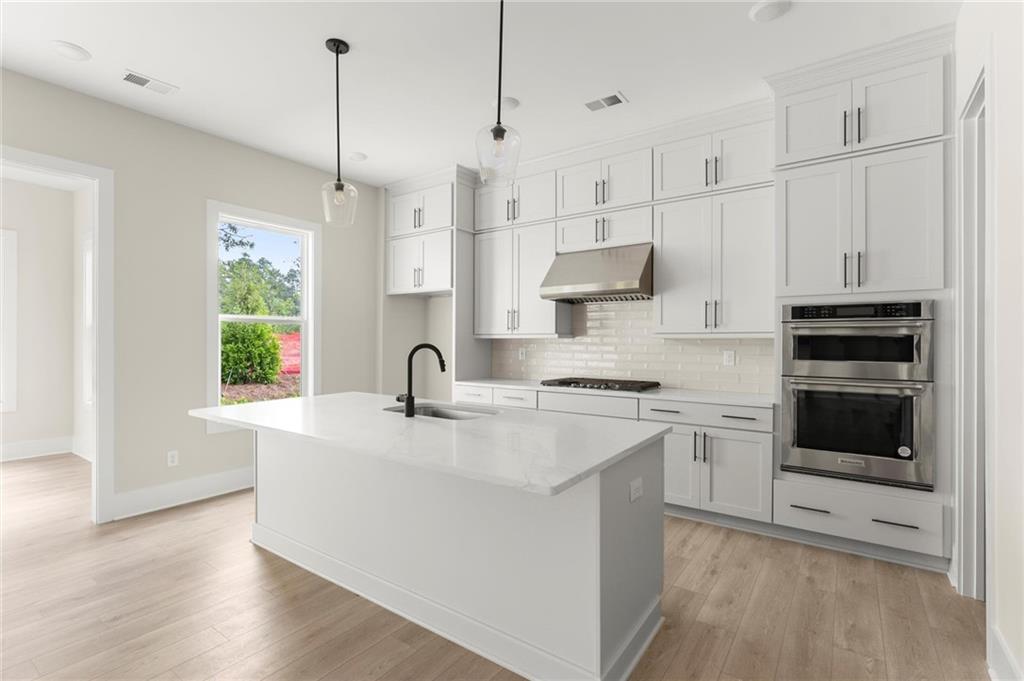 3552 Cedarvale Court Powder Springs, GA 30127 - Photo 11 of 46 a kitchen with stainless steel appliances granite countertop a sink a stove a refrigerator and white cabinets with wooden floor