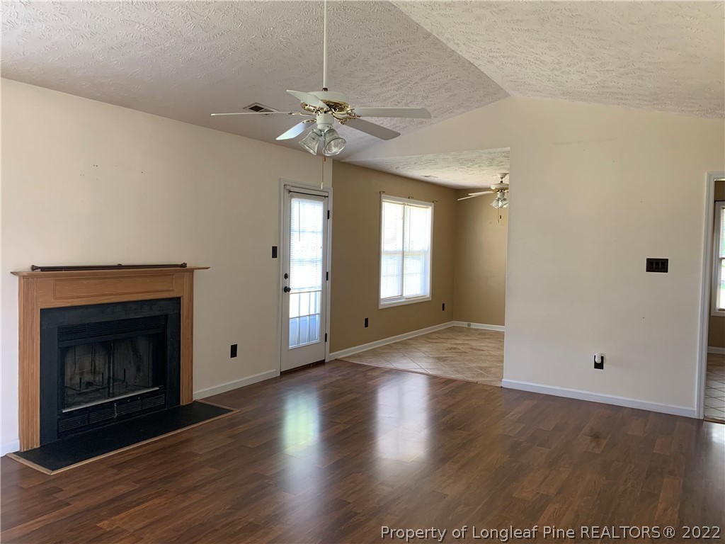 145 Rye Lane Raeford, NC 28376 - Photo 12 of 42 an empty room with wooden floor fireplace and windows