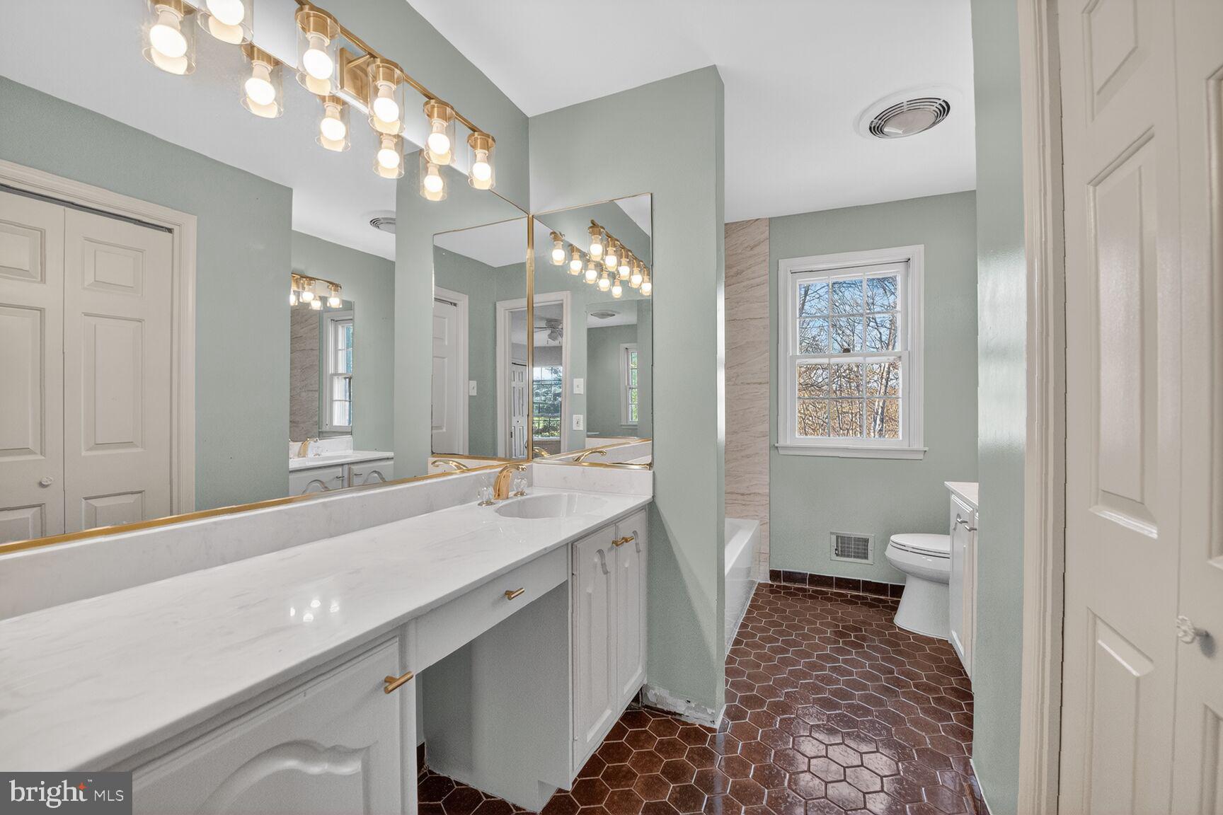 21733 Oatlands Road Aldie, VA 20105 - Photo 23 of 50 a spacious bathroom with a granite countertop sink a toilet and a mirror