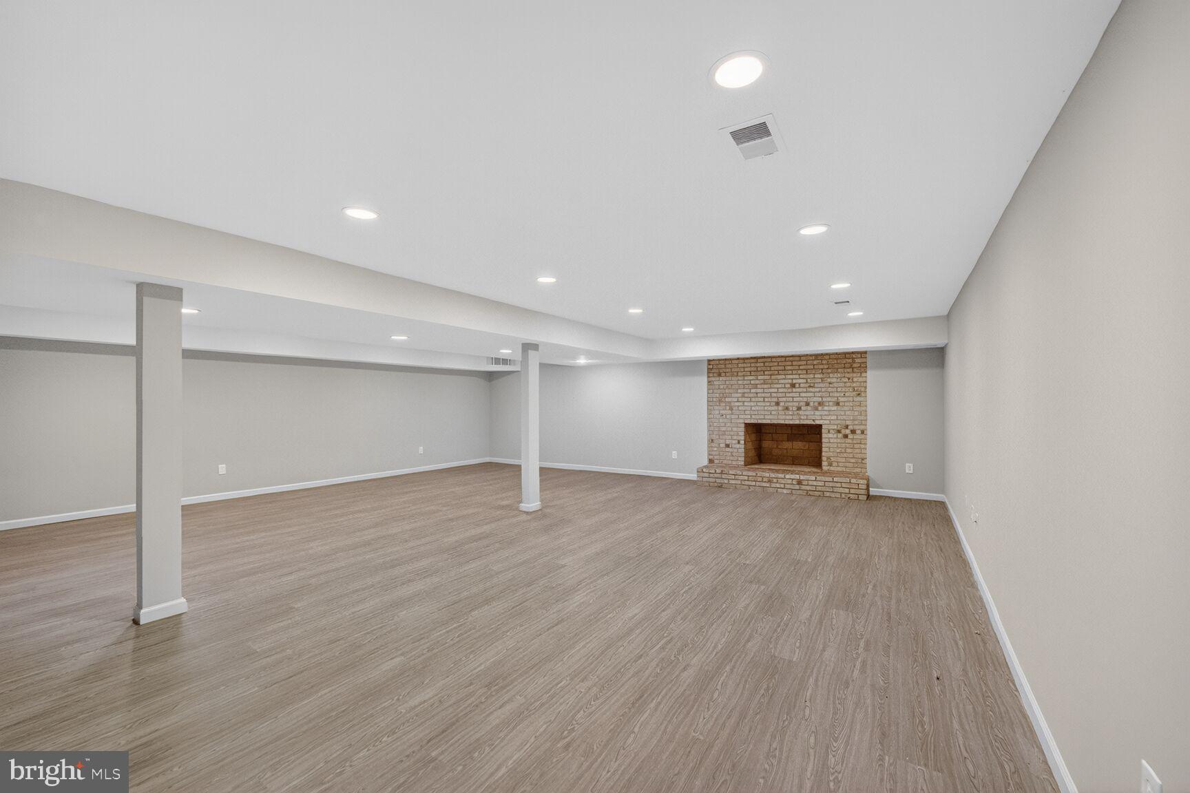 21733 Oatlands Road Aldie, VA 20105 - Photo 33 of 50 an empty room with wooden floor fireplace and windows