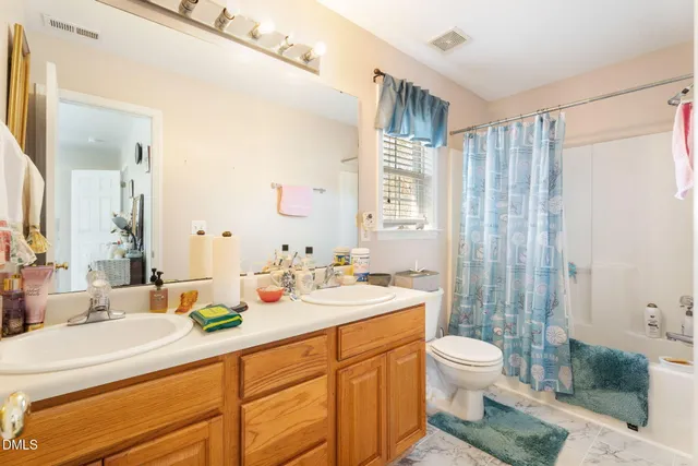 a bathroom with a double vanity sink toilet and shower