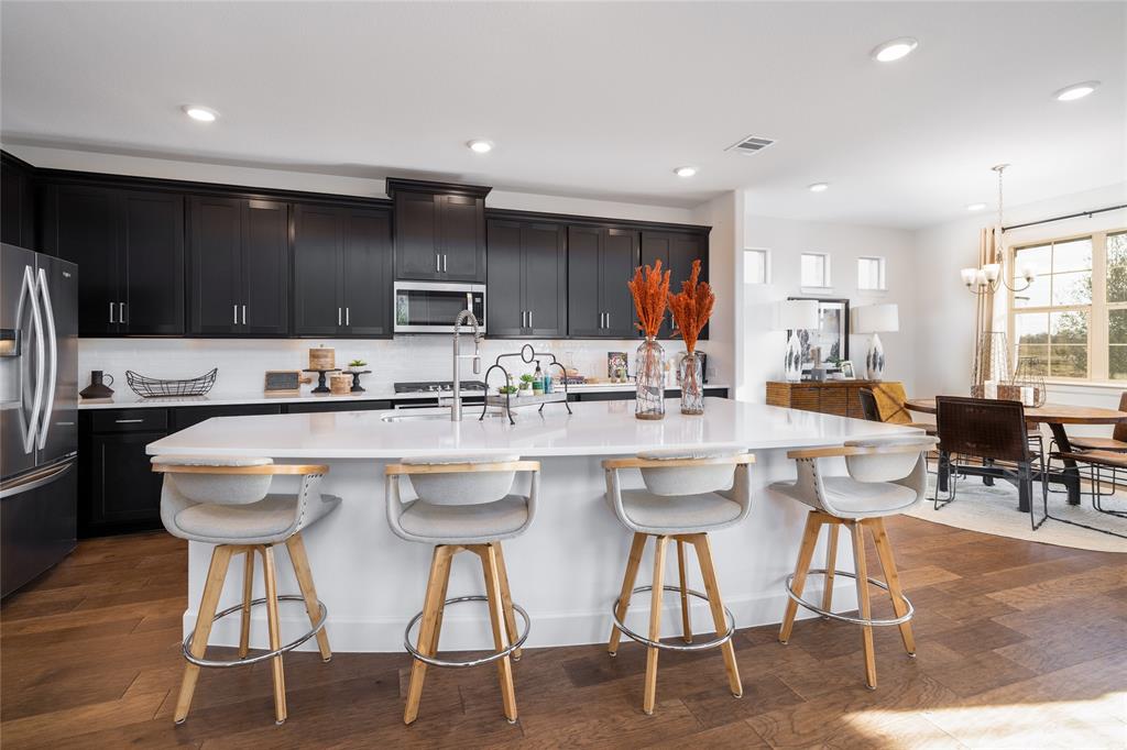 1428 Lady Bird Road Justin, TX 76247 - Photo 4 of 13 a kitchen with stainless steel appliances kitchen island granite countertop a stove a refrigerator a kitchen island and chairs with wooden floor