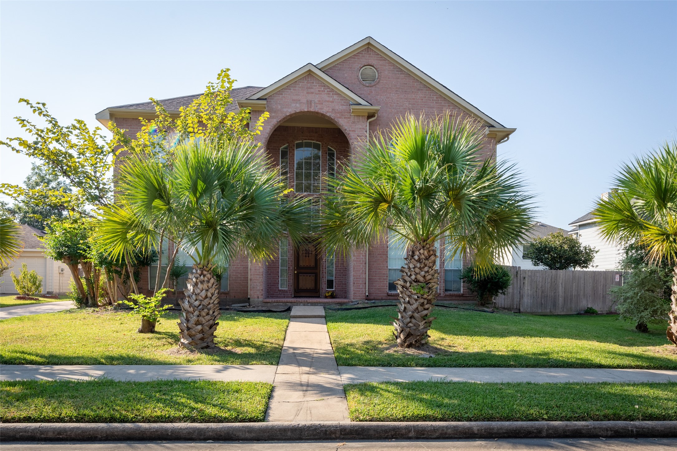 a front view of multi story residential apartment building with yard and green space