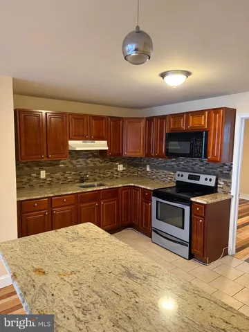 a kitchen with stainless steel appliances granite countertop wooden cabinets a stove top oven a granite counter and a sink