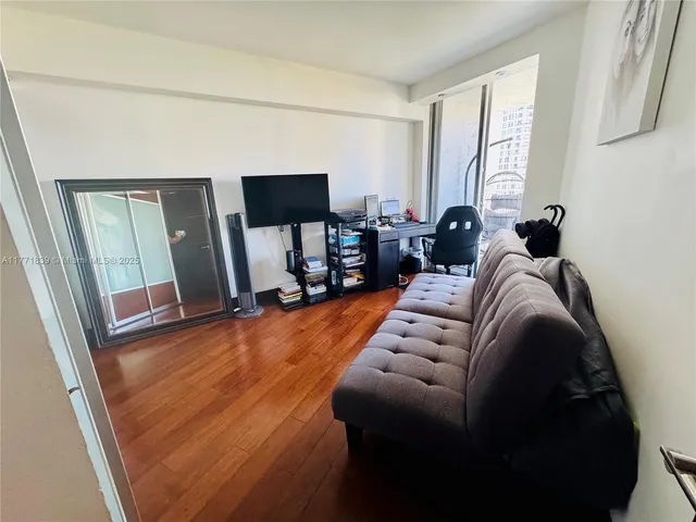 a living room with couches and kitchen view with wooden floor
