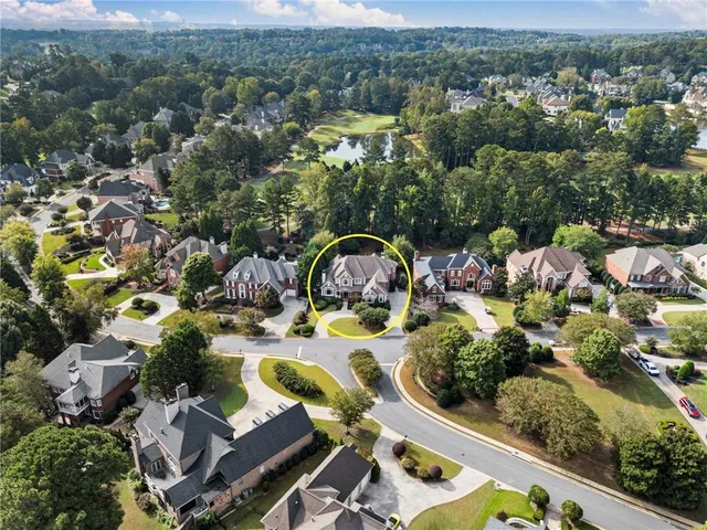 a view of a patio with table and chairs under an umbrella with large trees