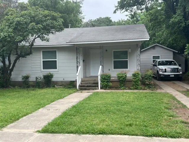 a view of a house with a yard plants and a large tree