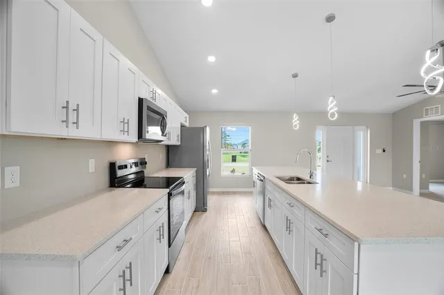 a large kitchen with stainless steel appliances granite countertop a lot of counter space and wooden floors