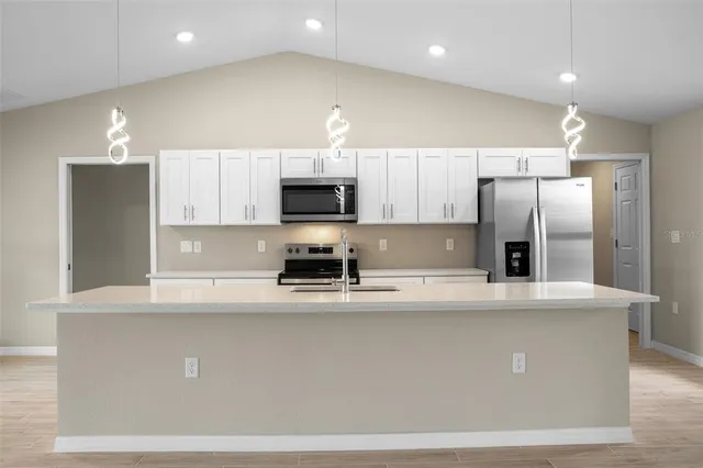 a kitchen with kitchen island a white cabinets and refrigerator