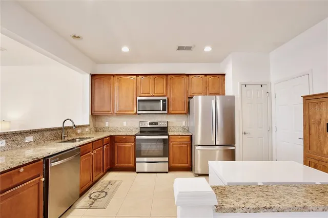 a kitchen with stainless steel appliances granite countertop a refrigerator a sink a stove a microwave and island