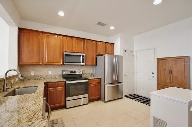 a kitchen with granite countertop a refrigerator and a stove top oven