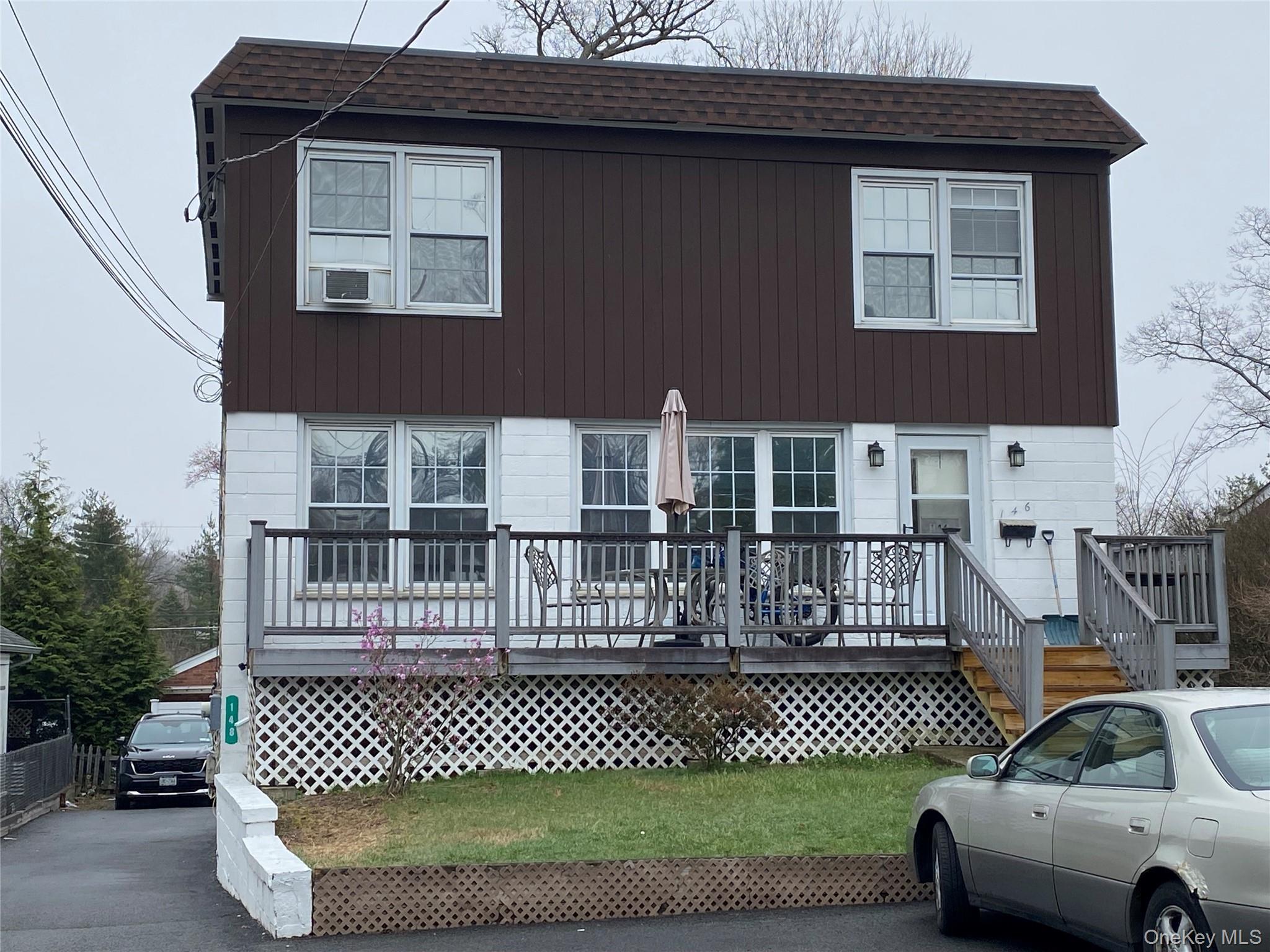 View of front of property featuring a wooden deck and roof with shingles