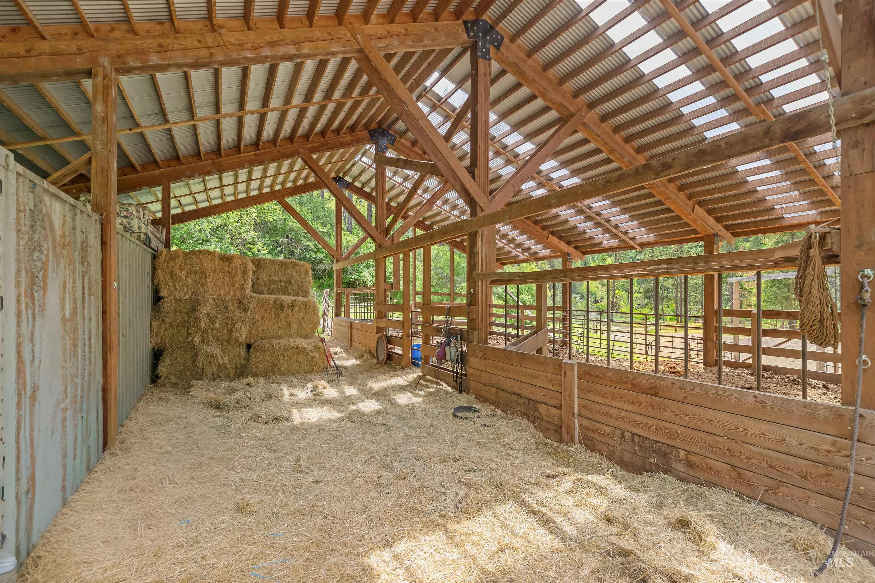 1314 Cedar Ridge Road Kendrick, ID 83537 - Photo 39 of 50 Open-air barn structure featuring exposed wood beams, a corrugated translucent roof, and a wood-paneled partition with metal bars