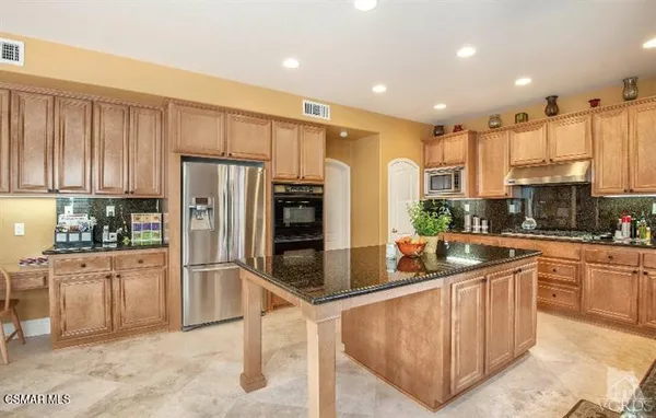 a kitchen with stainless steel appliances granite countertop a refrigerator oven a sink a stove and white cabinets
