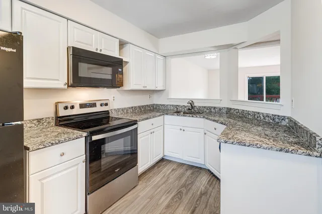 a kitchen with stainless steel appliances granite countertop a sink stove a microwave and wooden cabinets