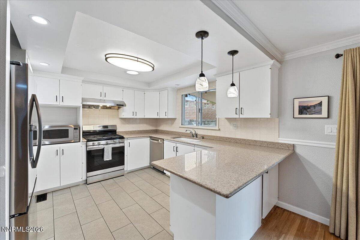 2205 Carlin Street Reno, NV 89503 - Photo 14 of 51 a kitchen with a stove a sink dishwasher a refrigerator and white cabinets with wooden floor