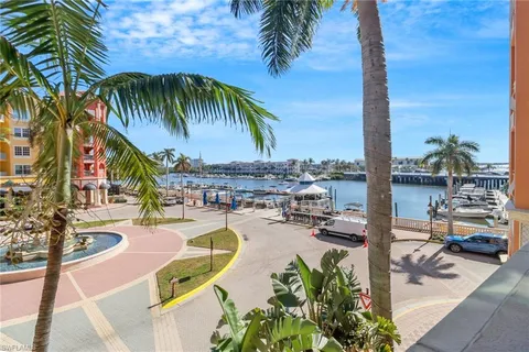a view of a swimming pool with a lawn chairs under palm trees