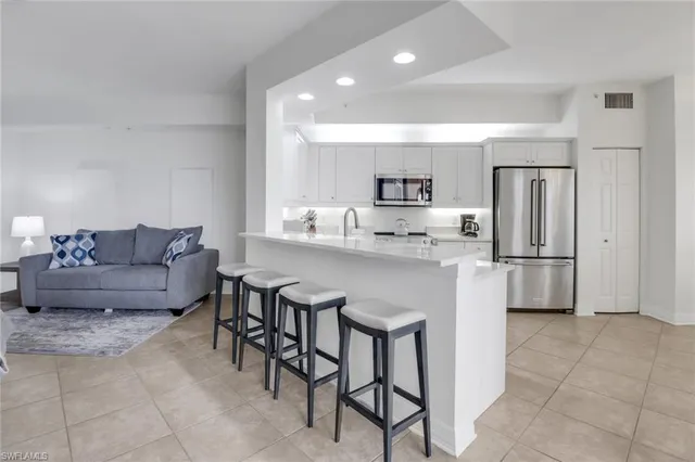 a living room with stainless steel appliances furniture a refrigerator and a kitchen island