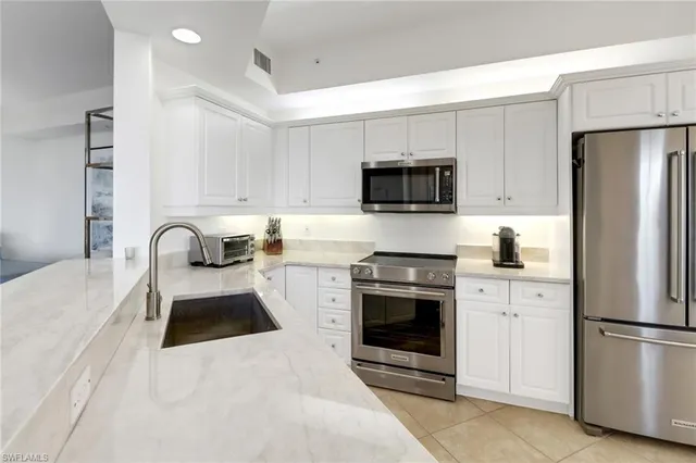 a kitchen with a refrigerator stove and white cabinets