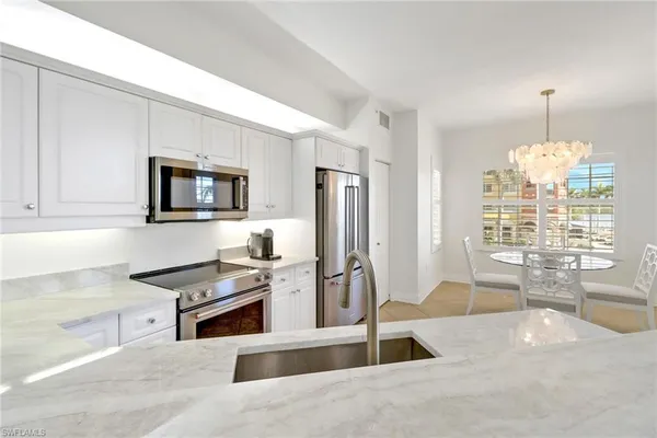 a kitchen with stainless steel appliances kitchen island granite countertop a stove top oven a sink a dining table and chairs
