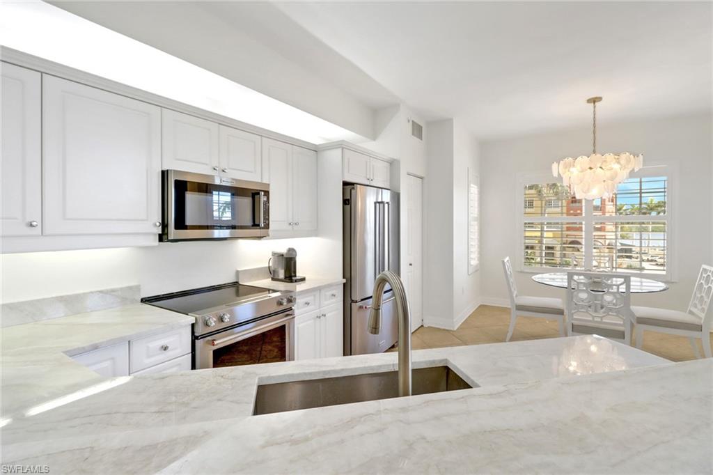 450 Bayfront Place, Unit 4206 Naples, FL 34102 - Photo 9 of 27 a kitchen with stainless steel appliances kitchen island granite countertop a stove top oven a sink a dining table and chairs