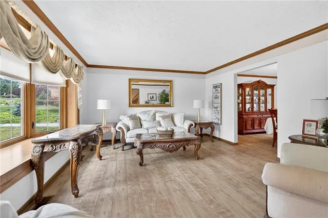 a living room with furniture two large window and a wooden floor