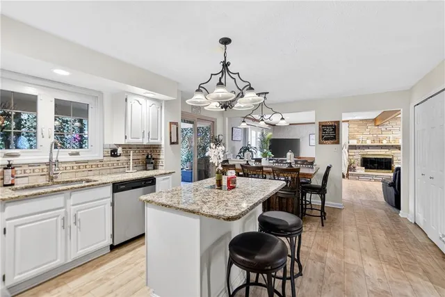 a kitchen with a granite countertop sink stove and white cabinets with wooden floor