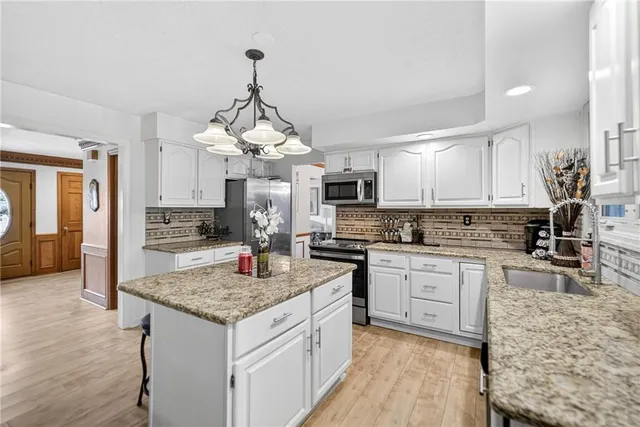 a kitchen with granite countertop kitchen island sink stove and white cabinets