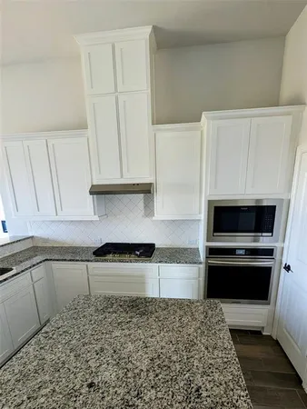 a kitchen with granite countertop white cabinets and stainless steel appliances