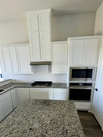 a kitchen with granite countertop white cabinets and stainless steel appliances