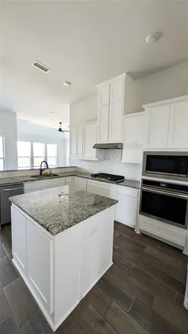 a kitchen with granite countertop a sink and a stove top oven