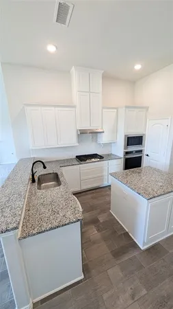 a kitchen with granite countertop a stove a sink and a refrigerator
