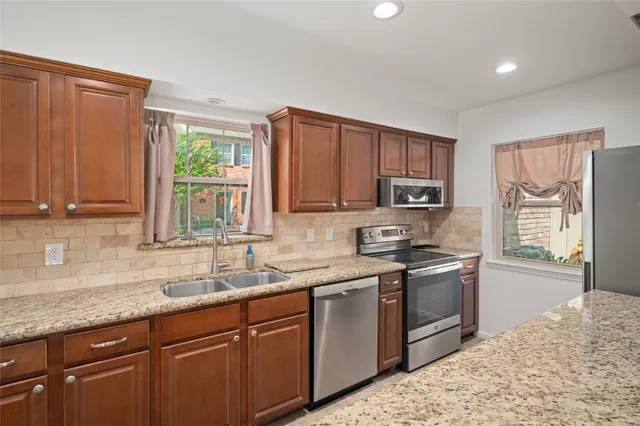 a kitchen with stainless steel appliances granite countertop wooden cabinets a sink and a stove
