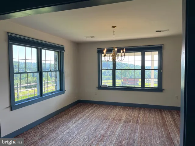 an empty room with wooden floor windows and kitchen view