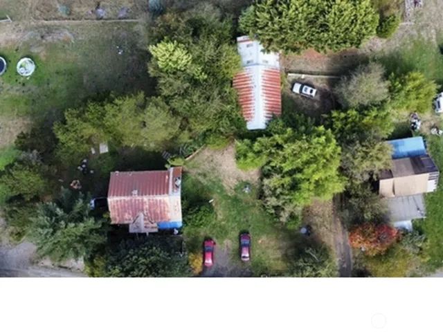 an aerial view of residential house with outdoor space and trees all around