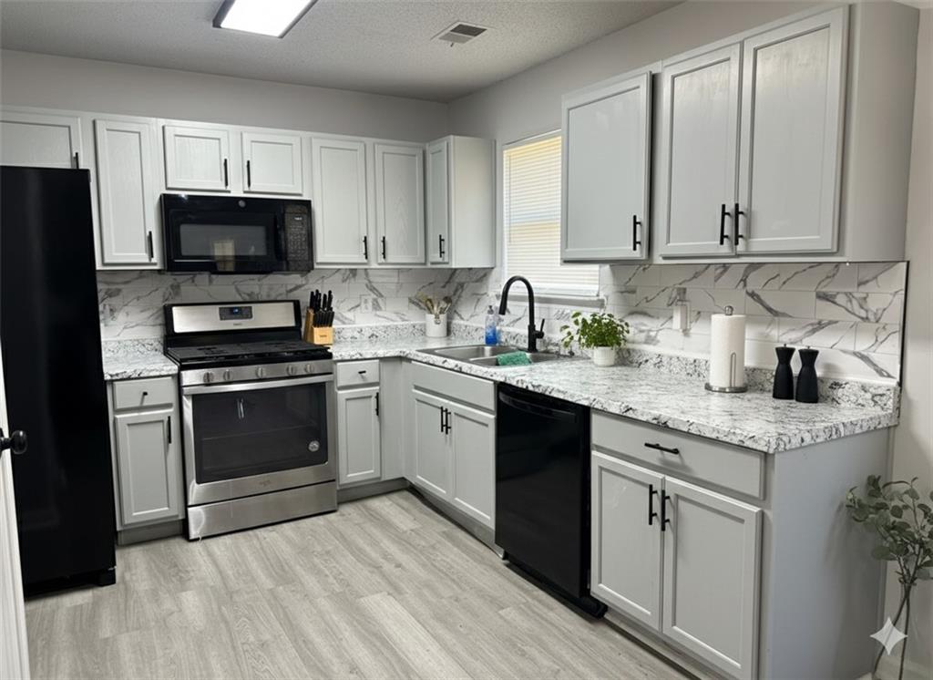 8258 Champion Trail Fairburn, GA 30213 - Photo 3 of 7 a kitchen with granite countertop a sink stainless steel appliances and cabinets