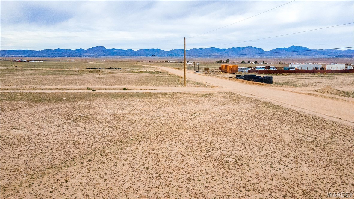 0 East Parker Road, Unit 119 Kingman, AZ 86401 - Photo 13 of 16 Expansive undeveloped land featuring a dirt road, distant mountains, and utility poles