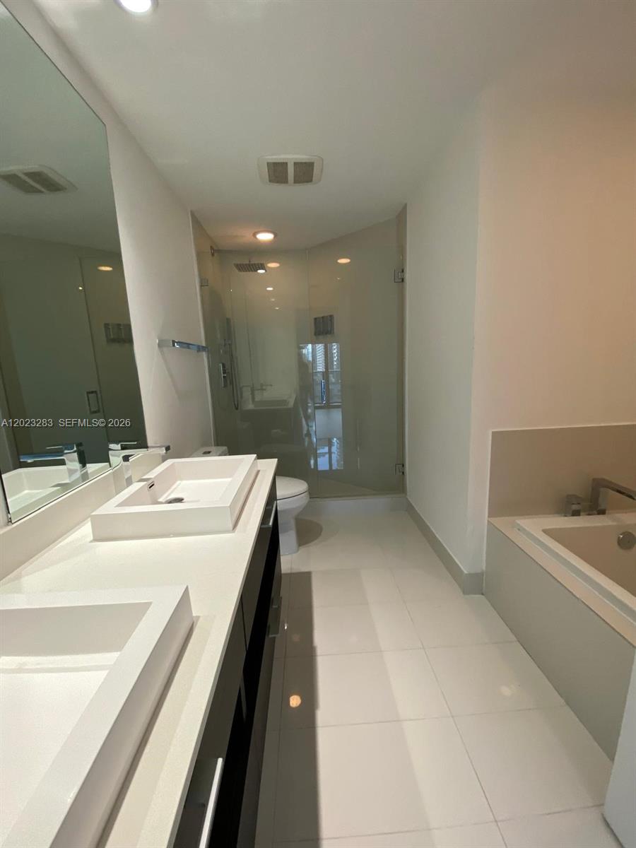 55 Southwest 9th Street, Unit 1503 Miami, FL 33130 - Photo 11 of 11 a spacious bathroom with a bathtub sink and mirror