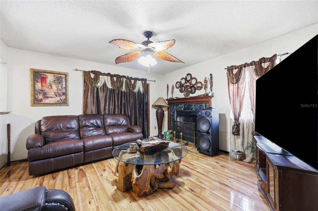 3027 Queens Gate Road Orlando, FL 32818 - Photo 11 of 34 a living room with furniture a fireplace and a flat screen tv