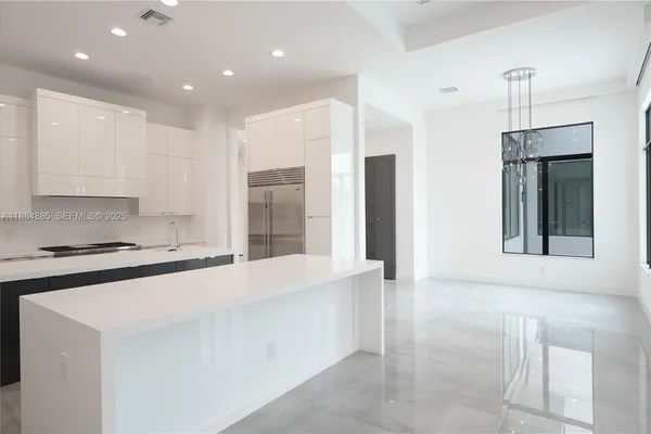 a large kitchen with stainless steel appliances a large counter top a stove and a refrigerator
