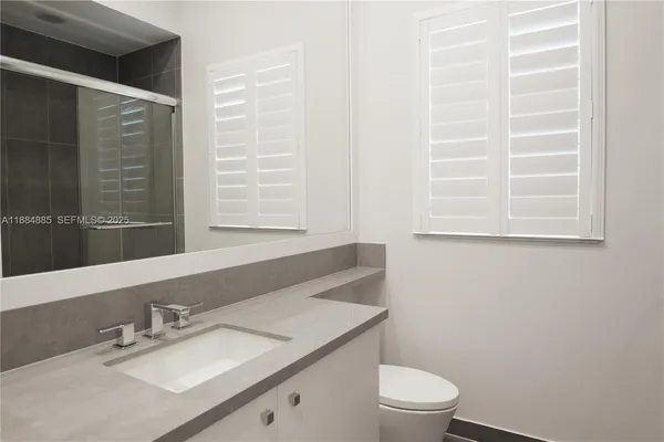 a bathroom with a granite countertop sink toilet a mirror and a window