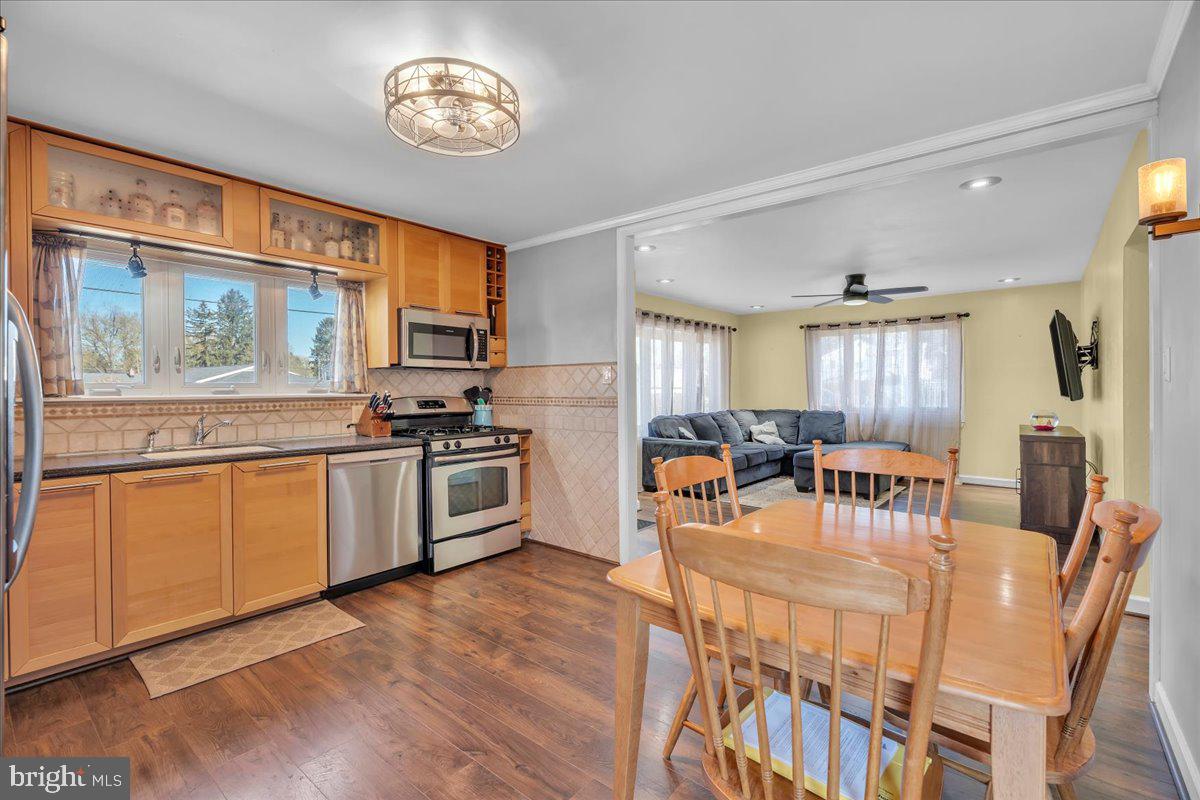 528 Rowand Avenue Glendora, NJ 08029 - Photo 9 of 24 a kitchen with stainless steel appliances granite countertop a stove top oven a refrigerator a dining table and chairs with wooden floor