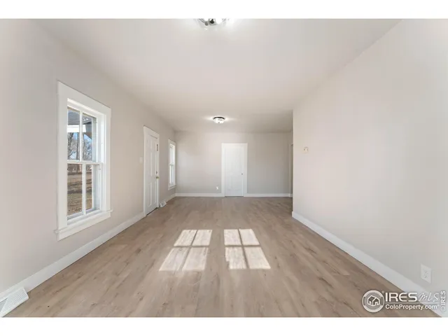 a view of an empty room with wooden floor and windows