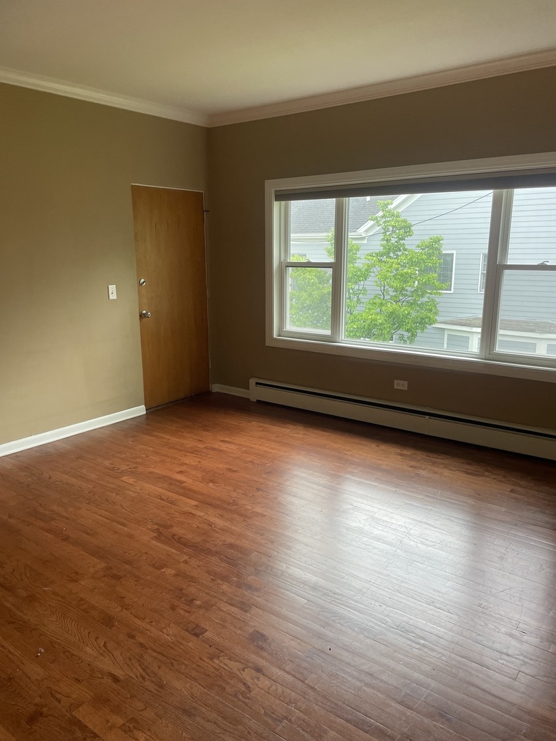 632 North Center Street, Unit 2W Naperville, IL 60563 - Photo 5 of 14 an empty room with wooden floor and windows with curtains