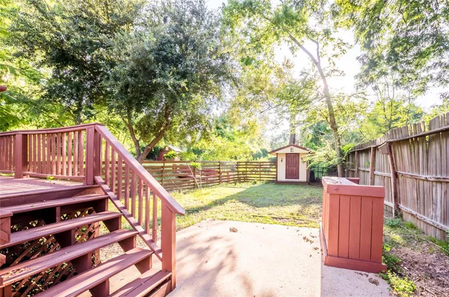 a view of backyard with wooden fence and large trees
