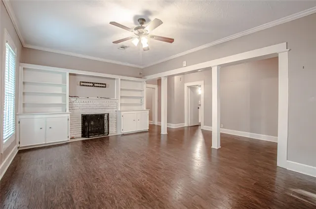 an empty room with wooden floor fireplace and windows