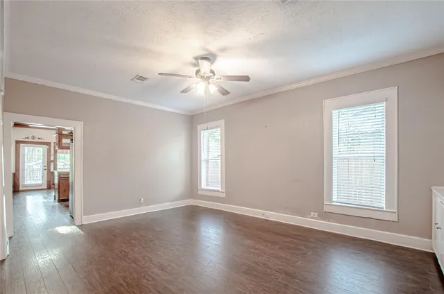 an empty room with wooden floor and windows
