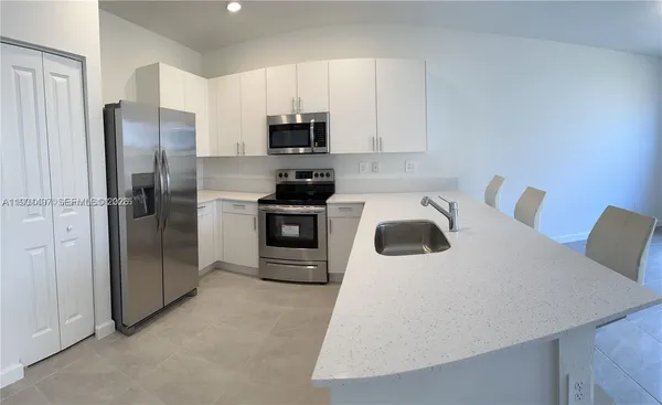 a kitchen with stainless steel appliances a refrigerator sink and white cabinets