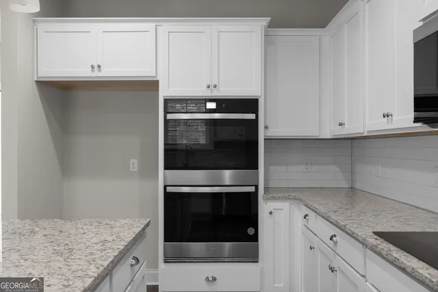 a kitchen with granite countertop white cabinets and stainless steel appliances